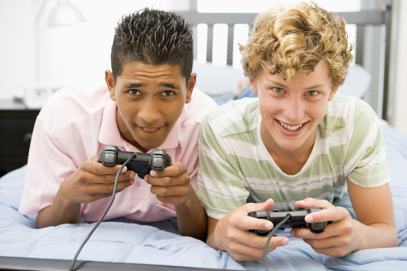 Two teenage boys playing video games together with controllers.