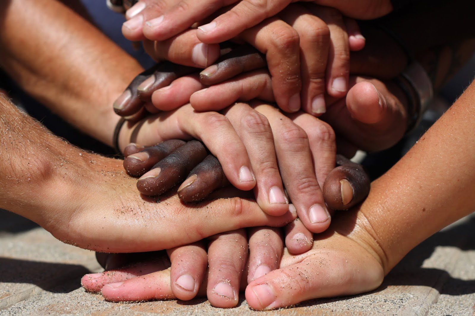 Hands of different skin tones interlocked, symbolizing unity and diversity.